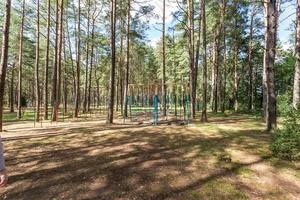 balanço e barras horizontais no playground e quadra de basquete na floresta de pinheiros foto