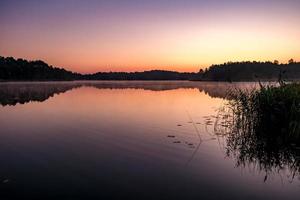 panorama no enorme lago ou rio de manhã com lindo nascer do sol rosa incrível foto