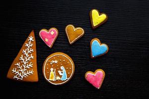 biscoitos de gengibre festivos artesanais em forma de estrelas, flocos de neve, pessoas, meias, funcionários, luvas, árvores de natal, corações para férias de natal e ano novo em fundo preto de madeira foto