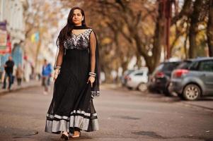 menina bonita indiana no vestido preto saree posou ao ar livre na rua outono. foto