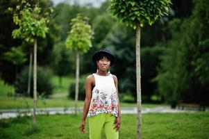 incrível mulher modelo americano africano em calças verdes e chapéu preto posou no parque. foto