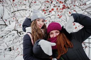 duas amigas engraçadas se divertindo no dia de inverno nevado perto de árvores cobertas de neve. foto