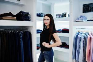 menina linda morena na boutique da loja de roupas em roupas casuais, camisa preta e jeans. foto