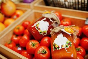 legumes frescos brilhantes coloridos. tomates com suco de tomate caseiro e artesanal de conservas na prateleira de um supermercado ou mercearia. foto