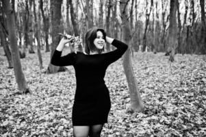 retrato de menina morena de vestido preto em madeira de primavera. foto