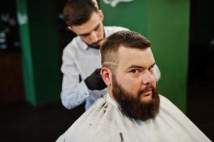 homem barbudo bonito na barbearia, barbeiro no trabalho. foto