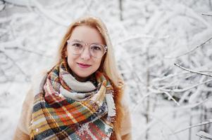 retrato de menina loira de óculos, casaco de pele vermelho e cachecol em dia de inverno. foto