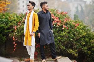 dois amigos indianos elegantes em roupas tradicionais posaram ao ar livre. foto