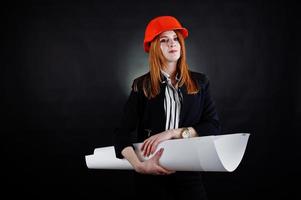 mulher engenheira em laranja proteger capacete com projeto de papel de construção. foto