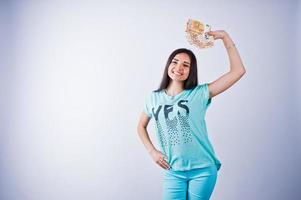 retrato de uma garota atraente em camiseta azul ou turquesa e calças posando com muito dinheiro na mão. foto