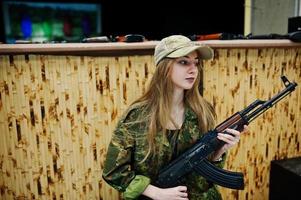 menina com metralhadora em mãos no campo de tiro. foto