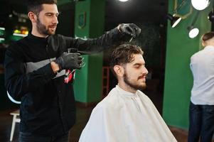 homem barbudo bonito na barbearia, barbeiro no trabalho. foto