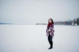 menina morena de suéter verde e lenço vermelho com lago congelado ao ar livre xadrez no dia de inverno à noite. foto