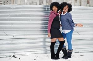 duas mulheres afro-americanas de cabelo encaracolado usam suéteres posados no dia de inverno. foto