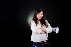 retrato de uma jovem de calça azul e blusa branca posando com megafone no estúdio. foto