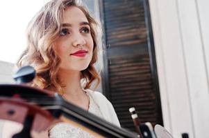 muito jovem gilrl músico vestido branco com contrabaixo. foto