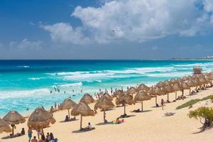 guarda-chuvas em uma praia de areia com água azul em um dia ensolarado perto de cancun, méxico foto