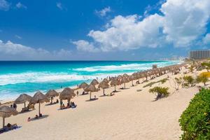 guarda-chuvas em uma praia de areia com água azul em um dia ensolarado perto de cancun, méxico foto