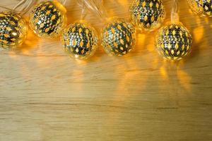 decoração de bola de luzes de ouro de natal na mesa de madeira. foto