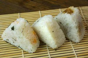 a comida japonesa onigiri arroz branco formado em formas triangulares ou cilíndricas e muitas vezes envolto em nori. foto