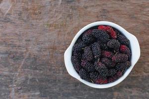 a fruta amoreira em tigela branca na mesa de madeira. foto