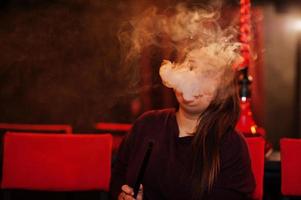 garota asiática fuma cachimbo de água no lounge bar. foto