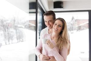 jovem casal desfrutando de café da manhã pela janela foto