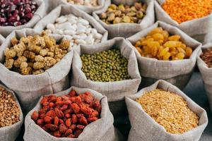 conceito de comida. close-up tiro recortado de vários tipos de cereais naturais e frutas secas em sacos. leguminosas em sacos. produtos para veganos