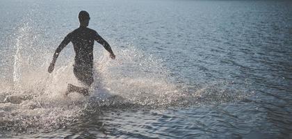 atleta de triatlo iniciando treinamento de natação no lago foto