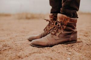 calçado que necessite de reparação. homem usa sapatos velhos com cadarços, fica no chão, posa ao ar livre. tiro recortado. bota de couro. sapatos de caminhada foto