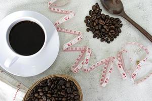 xícara de café e fundo de grãos de café com torneira de medida na mesa branca. foto