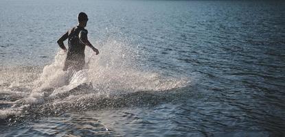 atleta de triatlo iniciando treinamento de natação no lago foto