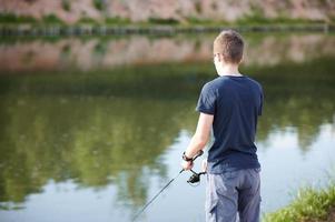 cara jovem pescando no lago com vara. férias de verão do conceito de estilo de vida de viagens.