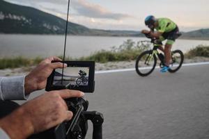 cinegrafista tomando uma foto de ação do atleta de bicicleta de triatlo