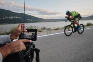 cinegrafista tomando uma foto de ação do atleta de bicicleta de triatlo