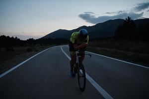 atleta de triatlo andando de bicicleta à noite foto