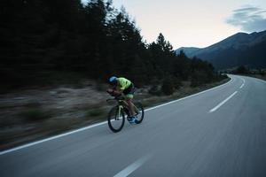 atleta de triatlo andando de bicicleta à noite foto