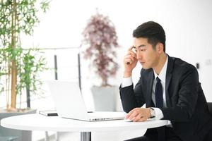jovem empresário asiático usando tablet, celular no escritório