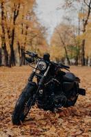 imagem vertical de moto preta no parque outono. motocicleta rápida ao ar livre para passeio. fotografia ao ar livre. conceito de transporte e temporada foto