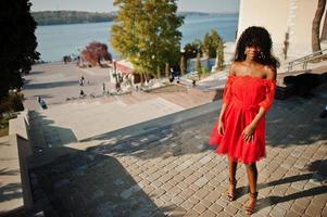 mulher encaracolada elegante na moda afro frança posou no dia de outono em vestido vermelho. modelo feminino africano negro. foto