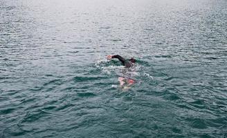 atleta de triatlo nadando no lago vestindo roupa de mergulho foto