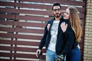 legal casal multirracial abraça junto com longboard contra cerca de madeira. foto