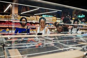 grupo de cinco mulheres africanas com carrinhos de compras escolhem arroz e outros grumos no supermercado. foto