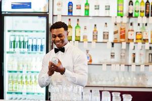 barman americano africano usa óculos de limpeza de gravata borboleta no bar. foto