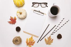 postura plana de outono ou conceito de estilo de ação de graças com café, folhas de outono, abóboras, café e prancheta em fundo branco foto