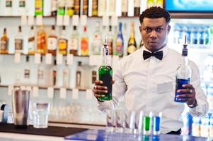 barman americano africano no bar fazendo coquetéis em tiros. preparação de bebidas alcoólicas. foto