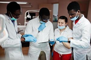 equipe multirracial de médicos dentistas. três médicos afro-americanos com uma médica caucasiana. discussão de momentos de trabalho. foto