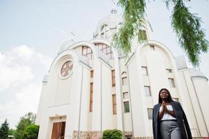 mulher afro-americana ao ar livre contra a igreja e reza a Deus. conceito de fé, espiritualidade e religião.