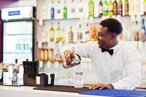 barman americano africano no bar com shaker. preparação de bebidas alcoólicas. foto