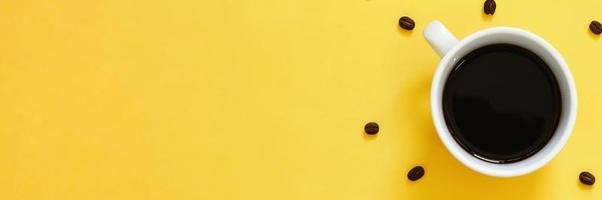 vista superior de café preto e grãos de café em fundo amarelo foto